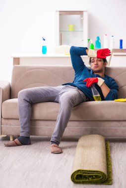 Genç adam evde ev işi yapıyor.