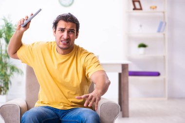 Genç adam evde televizyon izliyor.