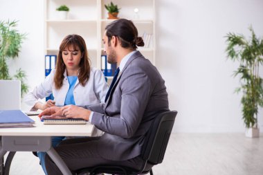 Genç bayan doktor ve hasta iş adamı ofiste.