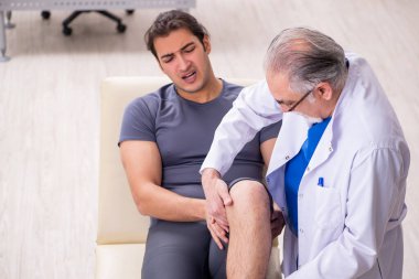 Genç erkek hasta yaşlı doktor travmatoloğu ziyaret ediyor.
