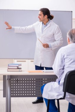 Deneyimli doktor genç erkek asistana öğretiyor.