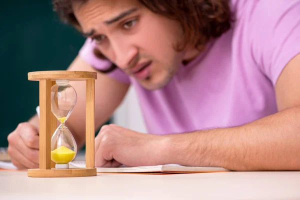 Jonge mannelijke student in het klaslokaal op tijdmanagementconcept — Stockfoto