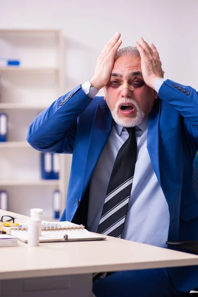 Old face injured employee sitting in the office — Stock Photo, Image