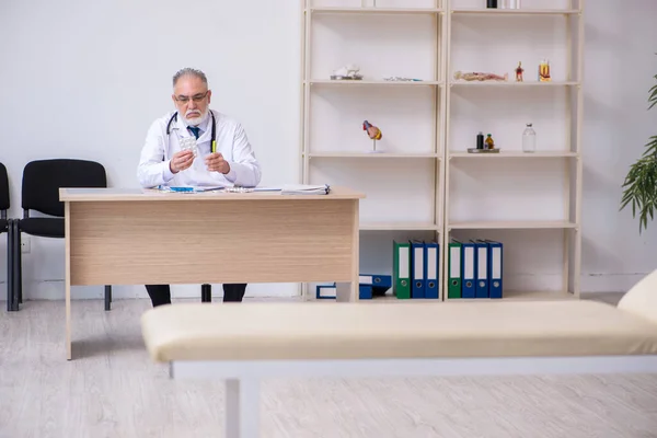 Vecchio medico di sesso maschile che lavora in clinica — Foto Stock