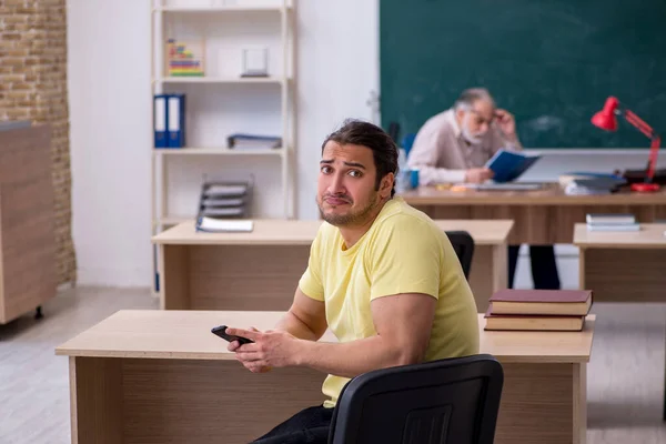 Old teacher and young male student in the classroom