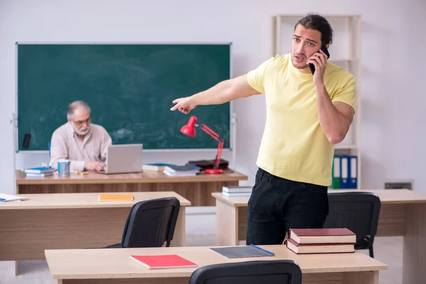 Old teacher and young male student in the classroom — Stock Photo, Image