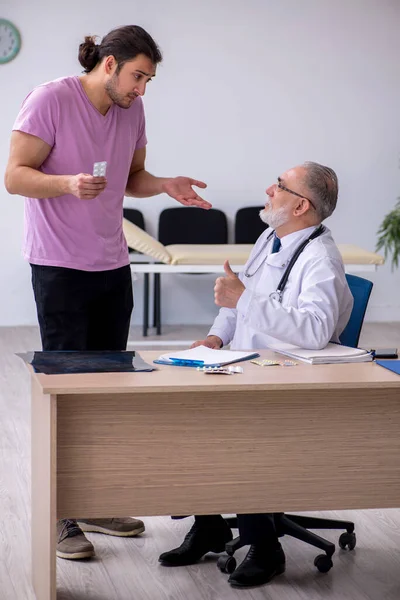 Ung manlig patient besöker gamla manliga läkare — Stockfoto