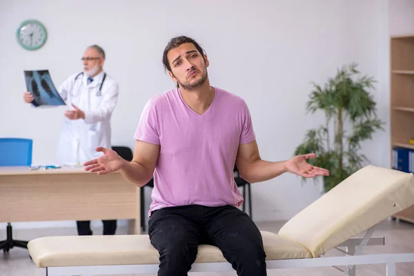 Old doctor radiologist examining young male patient