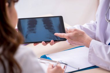 Yaşlı erkek doktor radyoloji uzmanı ve genç bayan asistanı.