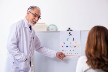 Genç kadın yaşlı erkek doktor göz doktorunu ziyaret ediyor.