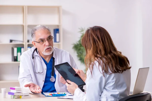 Yaşlı erkek doktor radyoloji uzmanı ve genç bayan asistanı. — Stok fotoğraf