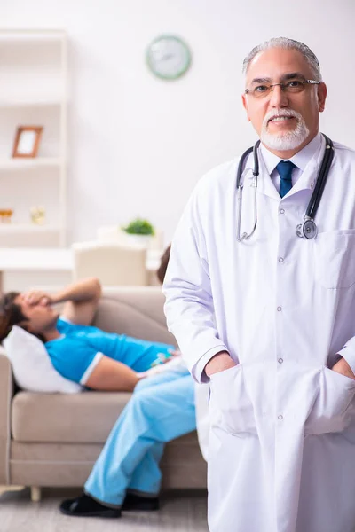 Two doctors visiting sick young man at home — Stock Photo, Image