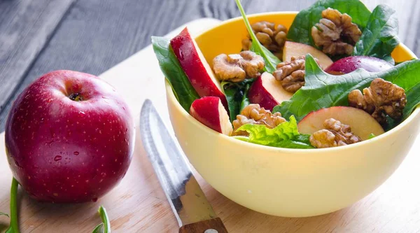 Salada de espinafre com nozes e maçãs servidas na mesa — Fotografia de Stock