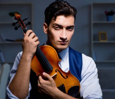 Genç müzisyen evde keman çalıyor.