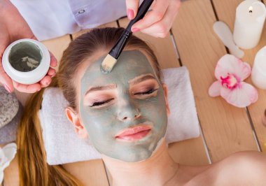 Yüz maskeli, spa sağlık konsepti olan genç bir kadın.