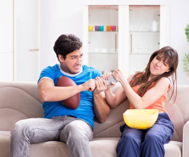 Adam karısıyla Amerikan futbolu seyrediyor.