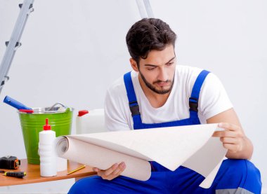 Tamirci, duvar kağıdıyla evde tadilat yapıyor.