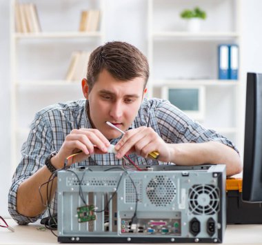 Genç teknisyen atölyede bilgisayar tamir ediyor.