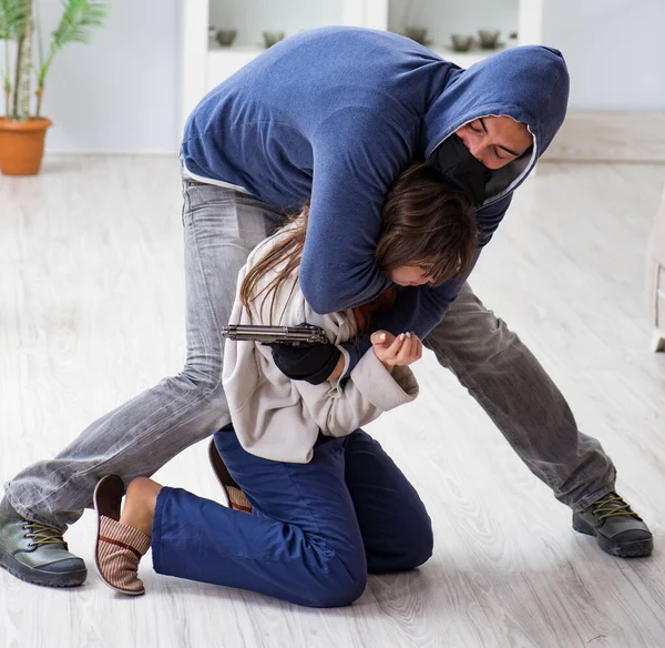 Armado homem assaltando jovem mulher em casa — Fotografia de Stock