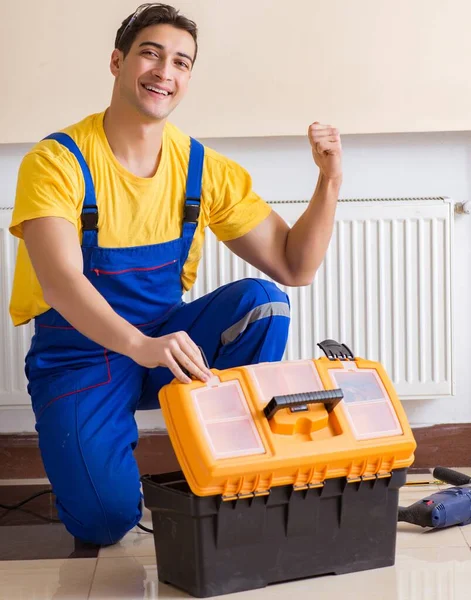 De jonge reparateur aannemer repareert verwarmingspaneel — Stockfoto