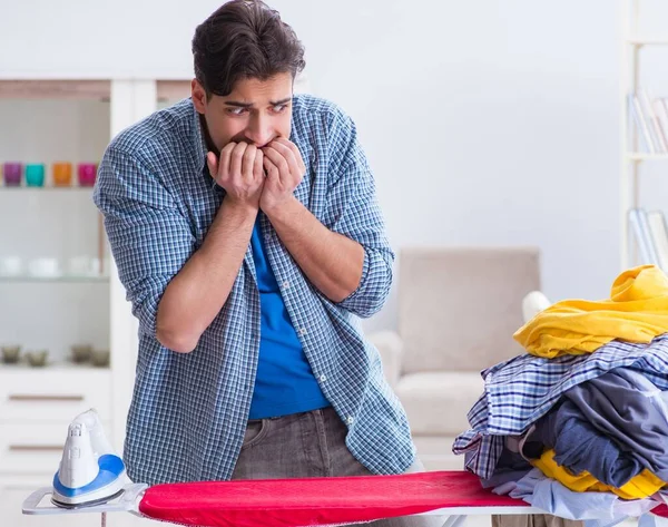 Joven marido haciendo planchado de ropa en casa — Foto de Stock