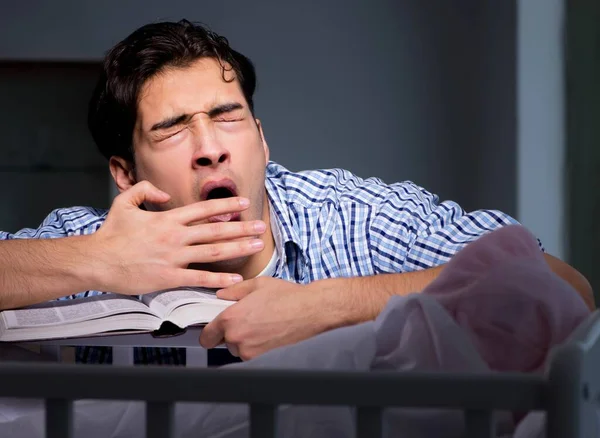 El joven estudiante haciendo los deberes y cuidando al bebé recién nacido — Foto de Stock