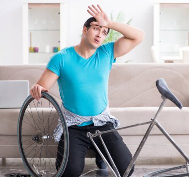 Evde bisiklet tamir eden genç bir adam.