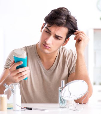 Genç yakışıklı adam aynaya bakıyor.