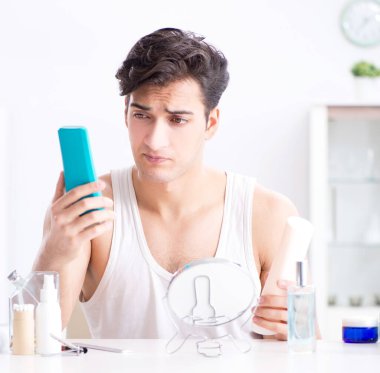 Genç yakışıklı adam aynaya bakıyor.