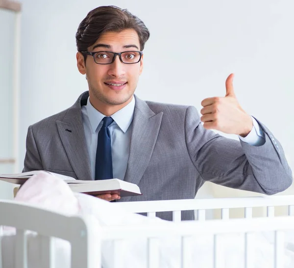 Jovem empresário tentando trabalhar em casa cuidando após o recém-nascido — Fotografia de Stock