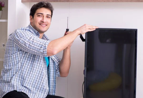 Man repairing broken tv at home