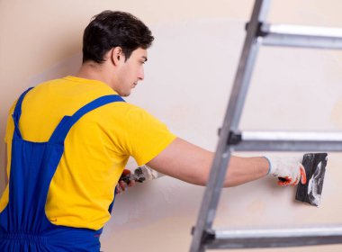 Duvara alçı yapıştıran genç müteahhit.