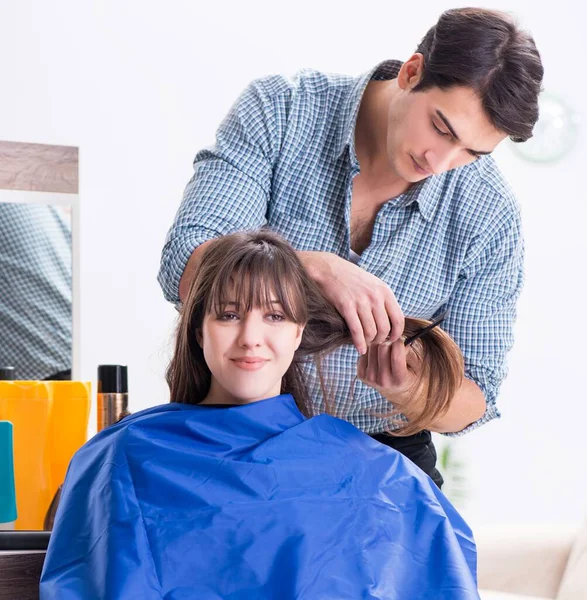 The man male hairdresser doing haircut for woman