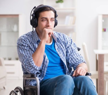 Tekerlekli sandalyede müzik dinleyen engelli adam.