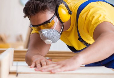 Genç bir marangoz dairesel testere ile çalışıyor.