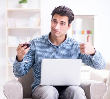 Genç adam evde şarap içiyor.