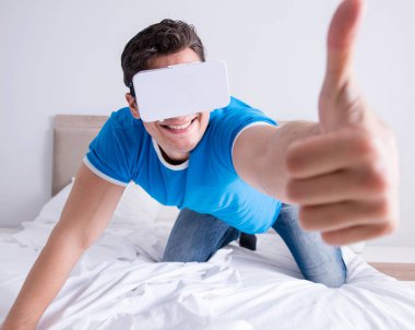 Yatakta sanal gerçeklik başlığı takan genç bir adam.