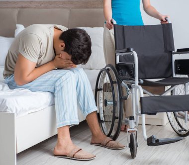 Üzgün karısıyla birlikte tekerlekli sandalyedeki umutsuz adam.