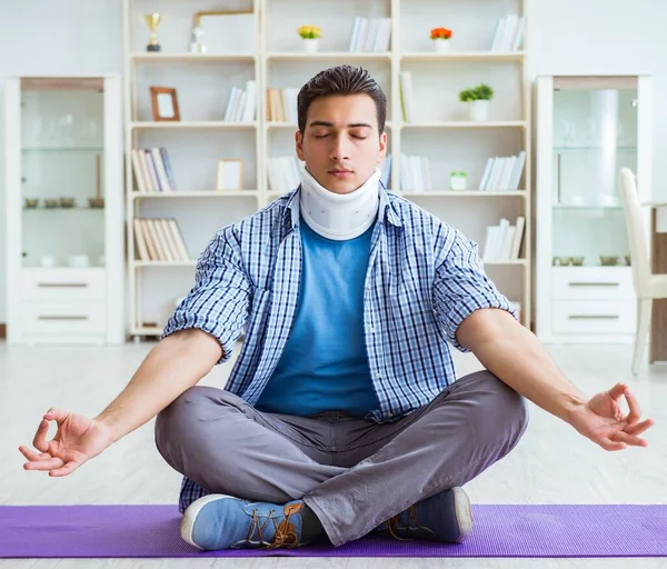 Мужчина с травмой шеи медитирует дома на полу — стоковое фото