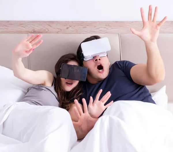 A esposa e o marido com óculos de realidade virtual na cama — Fotografia de Stock