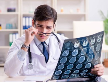 Genç doktor klinikteki röntgen görüntülerine bakıyor.