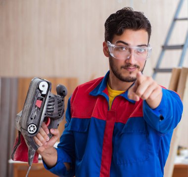 Elektrikli testereyle çalışan genç bir tamirci.