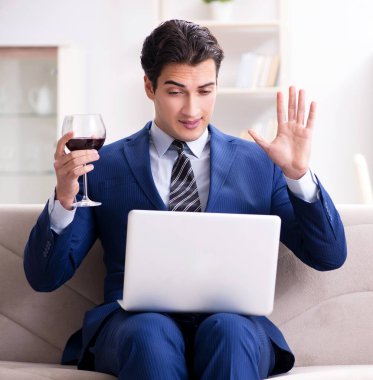 İş adamı evde oturmuş şarap içiyor.