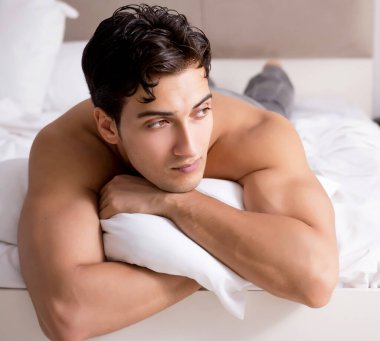 Genç yakışıklı gömleksiz adam gösteren çıplak gövde seksi yatakta s