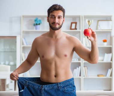 Kilo verme konseptinde büyük beden pantolon giyen bir adam.