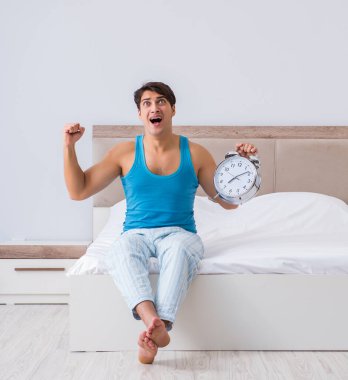 Genç adam yatakta uyanıyor.