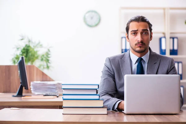 Ung manlig affärsman läser böcker på arbetsplatsen — Stockfoto