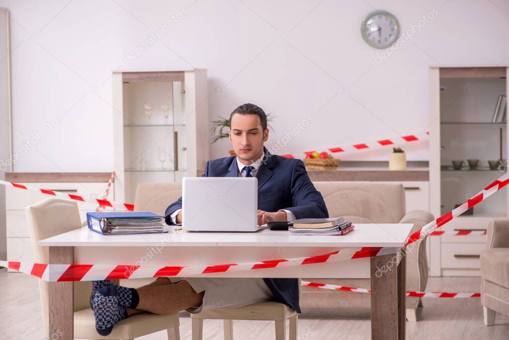 Young male employee working at home during pandemic disease