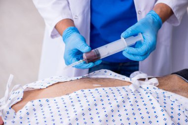 Yaşlı adam genç erkek stajyer doktoru ziyaret ediyor.