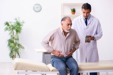 Yaşlı hasta genç erkek doktoru ziyaret ediyor.